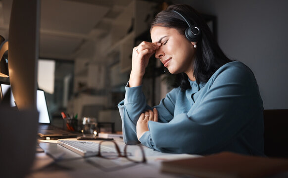 Stress, burnout and overtime, woman in call center with headache at crm office desk. Tired, frustrated and annoyed customer service consultant at computer working late at night with error or glitch.