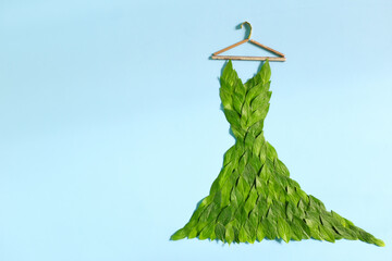 Sustainable and eco friendly fashion concept. Dress made of fresh green leaves in blue background.
