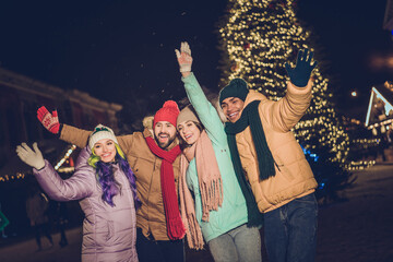 Portrait of group funny excited buddies arms waving hi have good mood x-mas evening lights outdoors