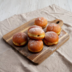 Homemade Apricot Polish Paczki Donut with Powdered Sugar on a Wooden Board, side view.