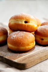 Homemade Apricot Polish Paczki Donut with Powdered Sugar on a Wooden Board, side view.