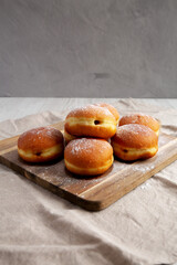Homemade Apricot Polish Paczki Donut with Powdered Sugar on a Wooden Board, side view. - obrazy, fototapety, plakaty
