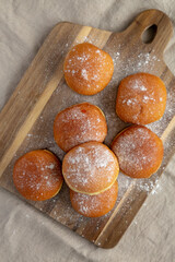 Homemade Apricot Polish Paczki Donut with Powdered Sugar on a Wooden Board, top view. Flat lay,...