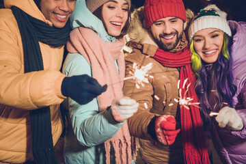 Cropped portrait of group positive carefree excited people arms hold bengal lights enjoy advent...