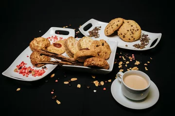 Fototapeten Top view of cookies on white plates with a cup of coffee on a black background © Diego Ignacio Riquelme Alvarado/Wirestock Creators