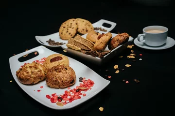 Stoff pro Meter Freshly made cookies on white plates with a cup of coffee on a black background © Diego Ignacio Riquelme Alvarado/Wirestock Creators