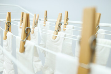 White socks hanging on drying rack on light background