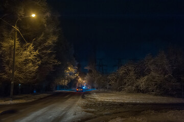 Snow-covered road against the background of night trees