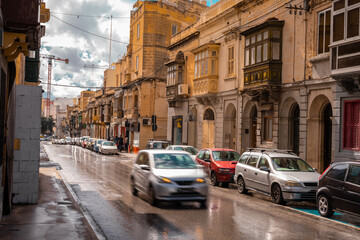 Road in the city of Valletta packed with cars and other traffic. Typical street in the mediterranean island of Malta on a rainy sunny day.