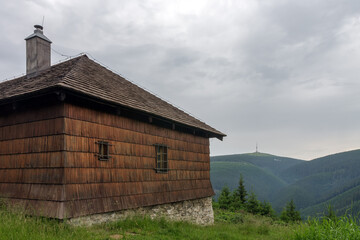 Fototapeta na wymiar Old hunting wooden cottage in Jeseniky mountains on a summer cloudy day