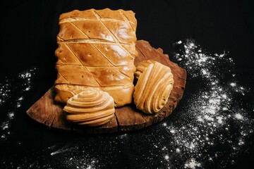 Top view of a wooden board with sweet puff pastry buns on a black background