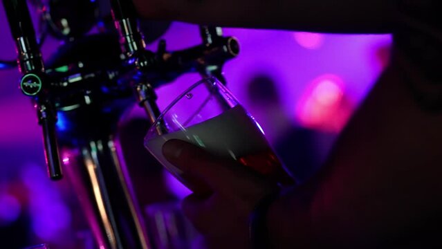 Night party, bartender pours beer into a glass, night club party, multicolored light.