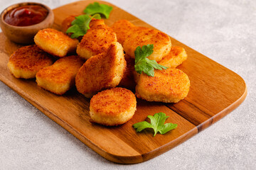 Fried crispy chicken nuggets on a wooden serving board.