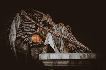 sculpture of death with a scythe and a lantern