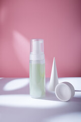 Foam care cosmetics bottle with concrete decor on pink backdrop, mockup template. Gentle intimate area cleanser for PH balance