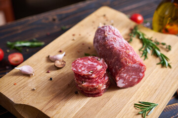 Traditional salami sausage on wooden cutting board with spices