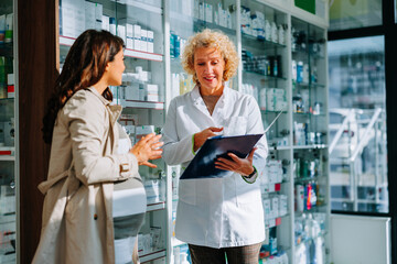 Pharmacist and pregnant woman in drugstore.