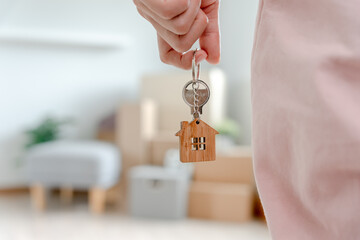 Moving house, relocation. Woman hold key house keychain in new apartment. move in new home. Buy or...