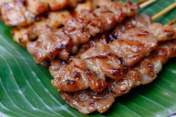 Grilled pork skewers on banana leaves. Traditional Thai-style grilled pork. Delicious and popular menu. Thai called 'Moo Ping'. Close-up photo. Asia food, Thai food.
