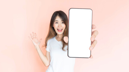 beautiful Asian young woman showing big smart phone with blank screen , white screen empty copy space for advertising banner isolated on pink background , Mock Up Image