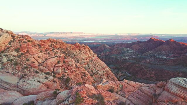Stunning Aerial Reveal of Red and Orange Mountains and a Green Valley in Yant Flats, Utah at Sunset near St. George, Utah.  This location is also referred to as Candy Cane Cliffs.