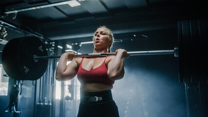 A Focused Female Bodybuilder Lifts Barbell with Heavy Weights in a Hardcore Gym Workout. Portrait...