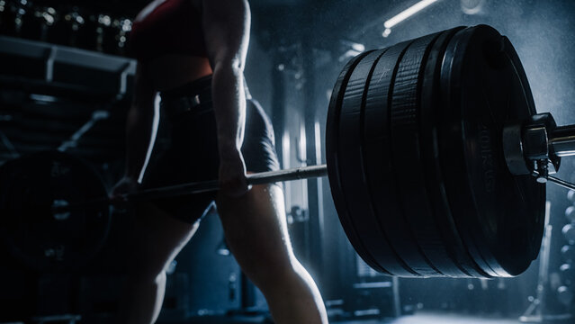 Focused Shot on a Heavy Barbell with the Body of a strong Woman Lifting it in the Background. An unstoppable Female Athlete Training, Exercising Overcomes The Challenge of Lifting Workout. Close Up