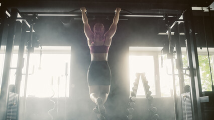 Contre-jour Aesthetic Shot: A Strong Woman Training with Pullups. Female Bodybuilder Doing Core...