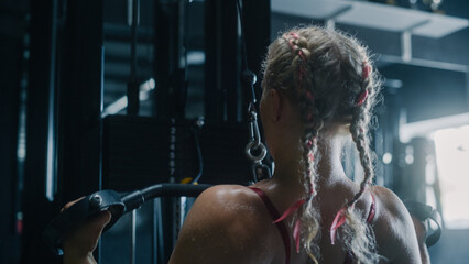 White Woman Doing Extreme Workout in a Hardcore Gym Using Lat Pull Down Machine. Portrait of a...