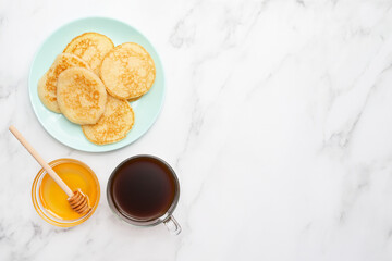 Delicious breakfast with coffee, pancakes and honey. Marble background. Place for text. Copy space. Happy morning concept. Top view. Flat lay.