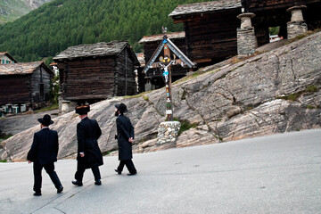 Orthodox Jews wearing black long coats and Shtreimel, walking in famous Swiss alpine resort - Saas...