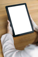 Digital mockup. Mobile technology. Online meeting. Female hands holding tablet computer blank screen sitting desk in light room interior.