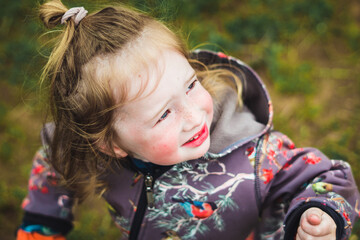 Highly sensitive, beautiful young boy child with long blond hair and colorful birds and trees jumpsuit out in nature.