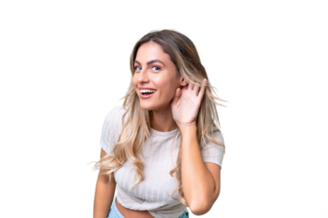 Young Uruguayan woman over isolated background listening to something by putting hand on the ear