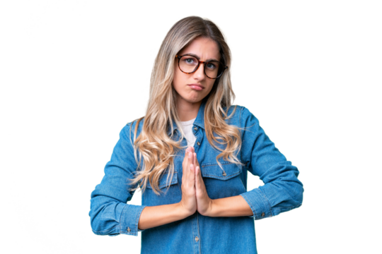 Young Uruguayan woman over isolated background keeps palm together. Person asks for something