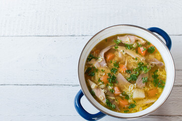 Pot with homemade chicken soup isolated on white background from above with copy space.