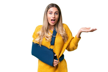 Young Uruguayan woman with broken arm and wearing a sling over isolated background with shocked facial expression