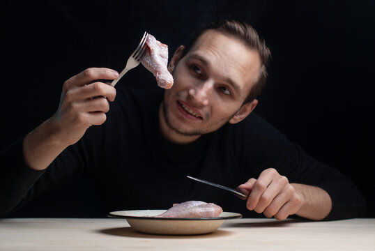 A Young Man Is Sitting At An Empty Table With A Plate Of Raw Chicken On It, The Concept Of A Bad Thanksgiving