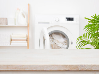 Empty wooden table in blurred laundry room with washing machine - obrazy, fototapety, plakaty