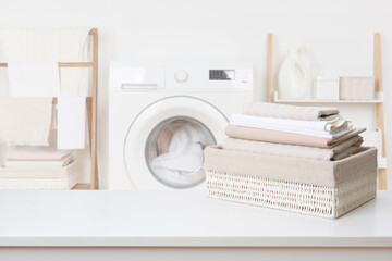 Clean laundry in basket on white table over blur bathroom