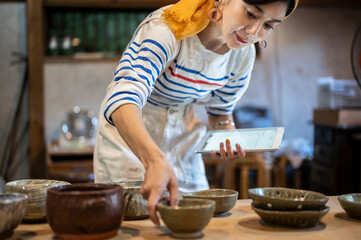 デジタルタブレットを使って商品管理をする陶芸家の女性