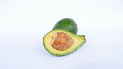 Green avocado fruit that has been split and is ripe. Contains many vitamins for human health. Placed on a white mat.
