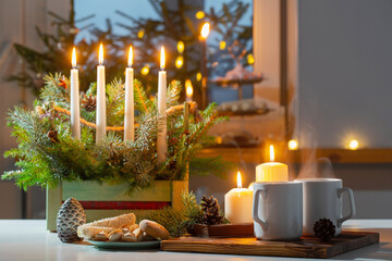 white cups with hot drink and christmas decorations at home