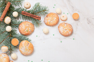 candies and cookies with christmas tree branches on white marble background