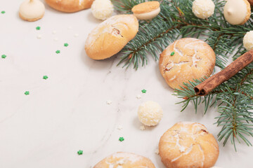 candies and cookies with christmas tree branches on white marble background