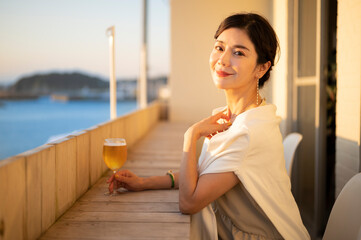 サンセットが美しい海辺のカフェでビールを飲む女性