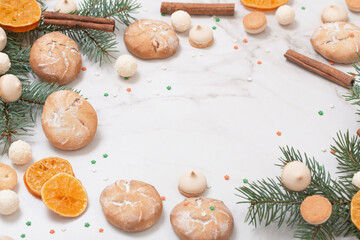candies and cookies with christmas tree branches on white marble background