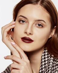Fototapeta premium Close-up portrait of young beautiful girl posing in stylish jacket isolated over white background. Deep red lips makeup. Concept of beauty, fashion and cosmetology