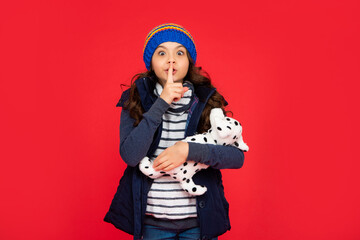 child in puffer jacket hold toy. teen girl on red background. happy childhood.