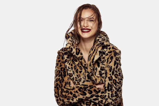 Portrait of young beautiful girl posing in stylish animal print coat and smiling isolated over white background. Concept of beauty, fashion and cosmetology